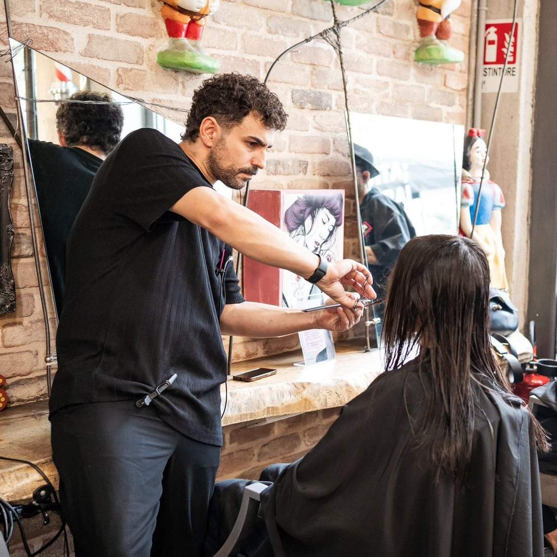 Un parrucchiere del team taglia i capelli a una cliente