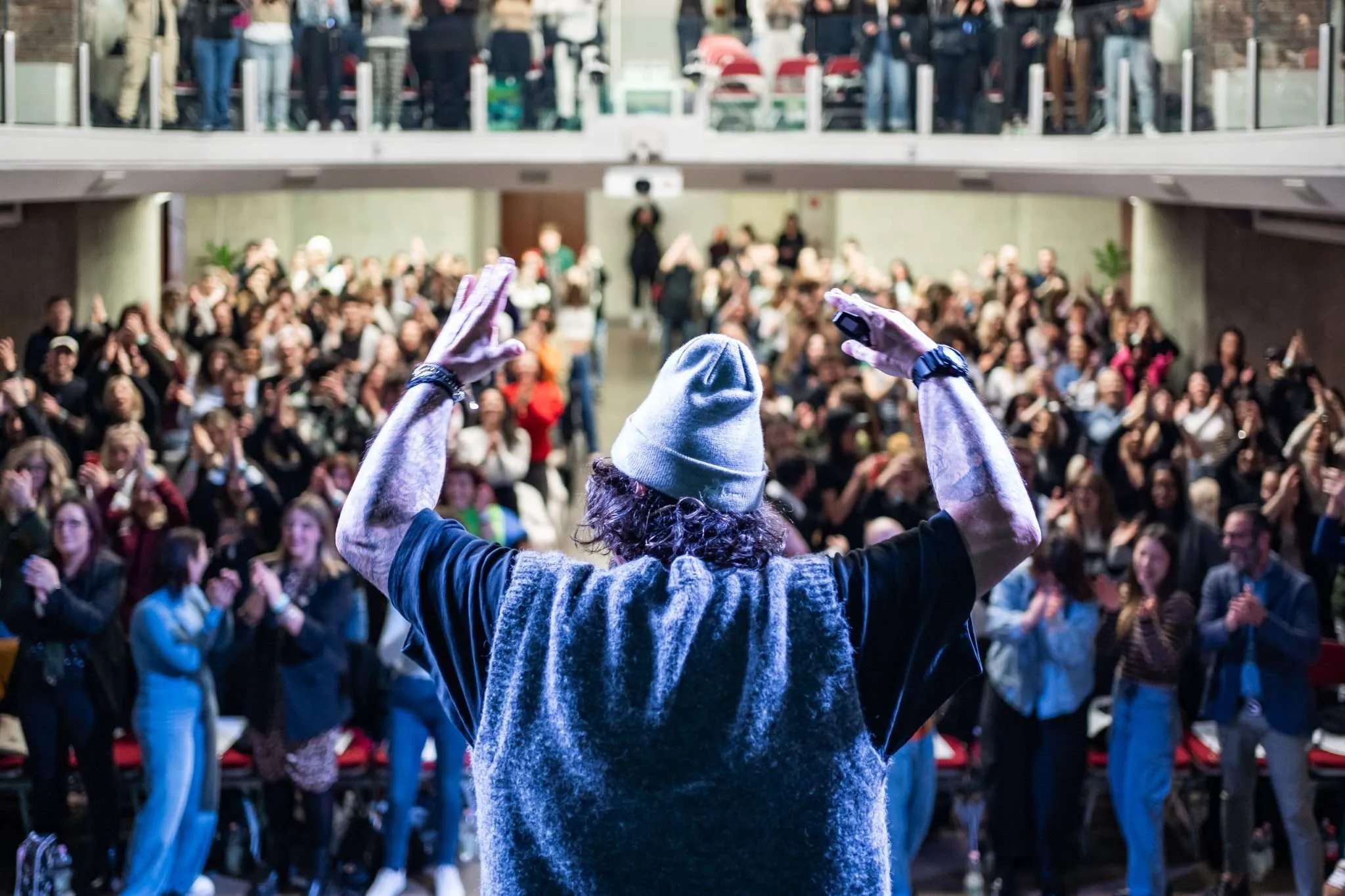 Luca Picchio di spalle sul palco, braccia alzate davanti al pubblico in piedi