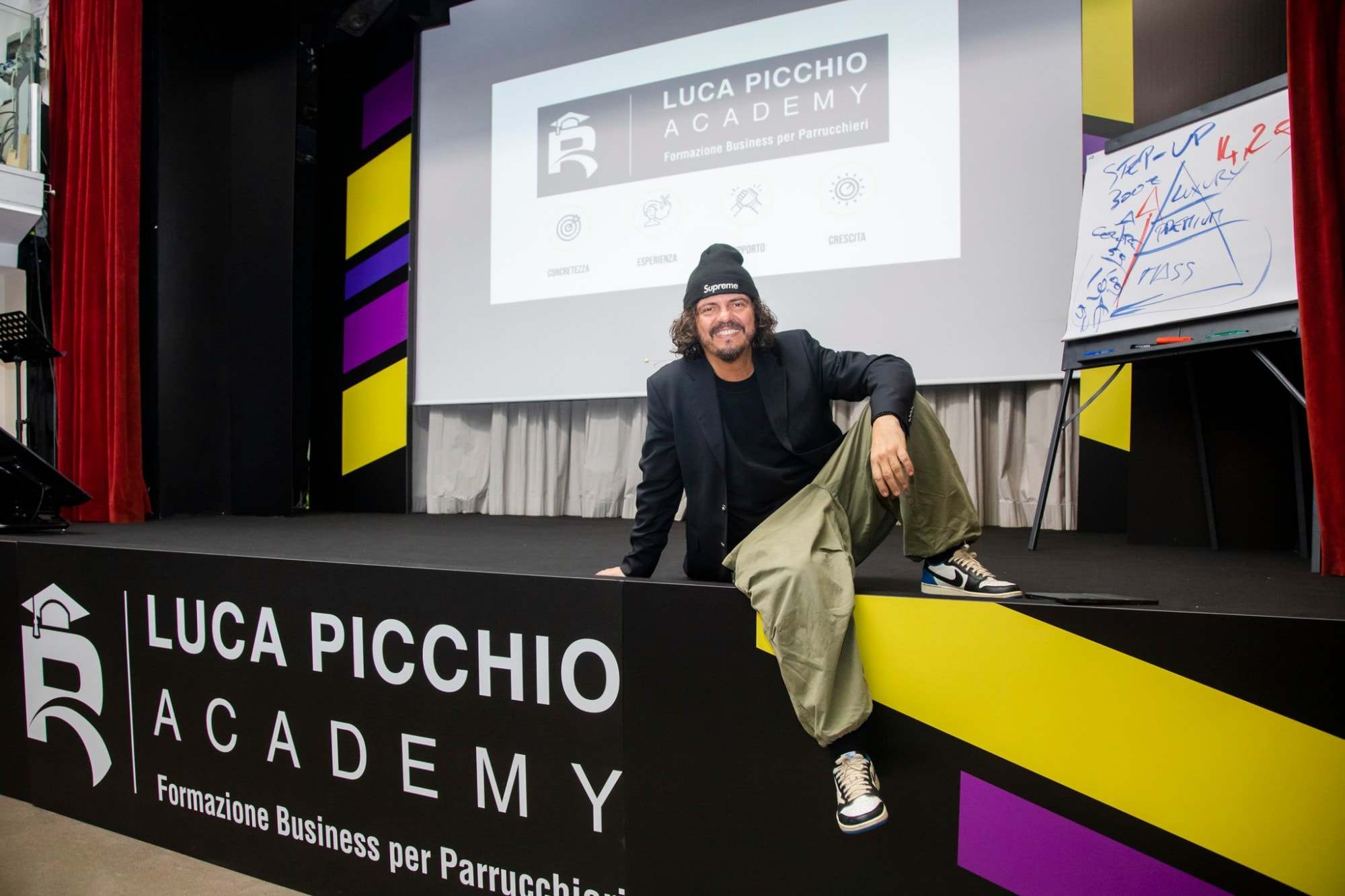 Luca Picchio sorridente, seduto sul bordo del palco della Luca Picchio Academy