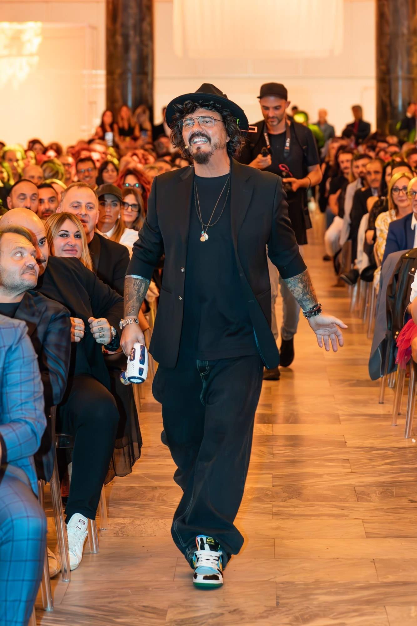 Luca Picchio sorridente cammina tra il pubblico seduto, durante un evento